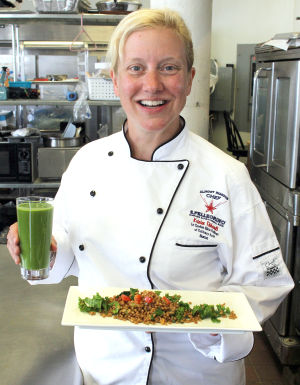 Kristen Thibeault, the owner of Kombu Kitchen in Lynn, holds a plate of wheatberry poblano kale salad and a glass of green goddess juice.